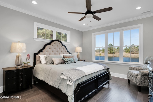 bedroom featuring ornamental molding, dark hardwood / wood-style flooring, multiple windows, and a water view