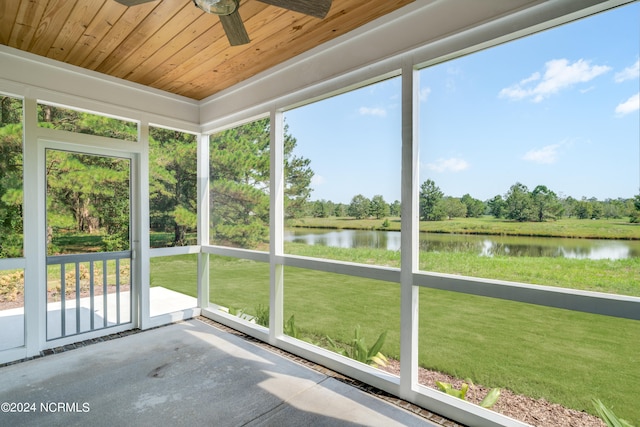 unfurnished sunroom with ceiling fan, a water view, a wealth of natural light, and wood ceiling