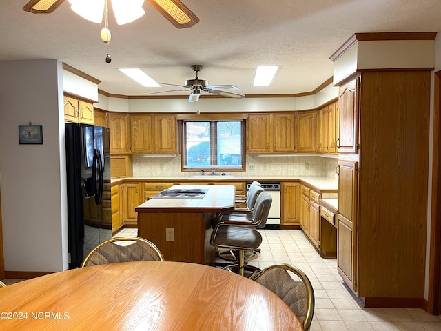 kitchen featuring black refrigerator with ice dispenser, backsplash, a kitchen island, ceiling fan, and white dishwasher