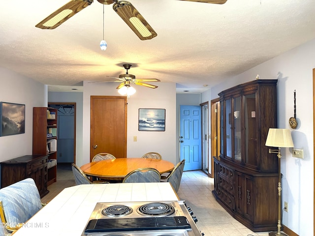 tiled dining space featuring a textured ceiling and ceiling fan