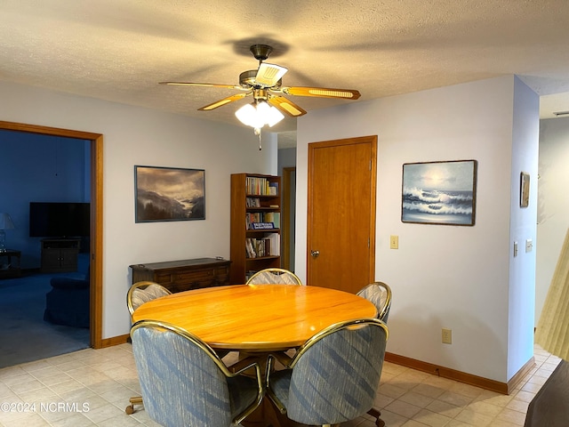 tiled dining space with ceiling fan and a textured ceiling