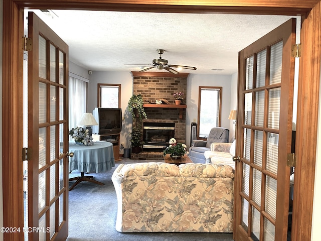 carpeted living room with french doors, a textured ceiling, ceiling fan, and a fireplace