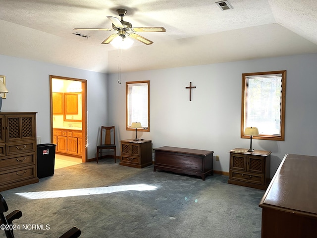 carpeted bedroom featuring a textured ceiling, ensuite bath, ceiling fan, and vaulted ceiling