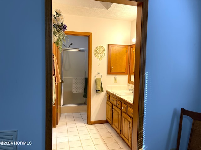 bathroom featuring vanity, a textured ceiling, tile floors, and walk in shower