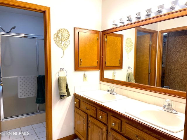 bathroom featuring a shower with shower door, oversized vanity, tile floors, and double sink