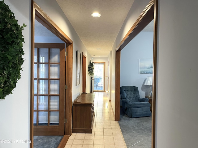 hall with a textured ceiling and light tile flooring