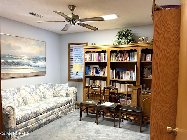 sitting room with ceiling fan, light colored carpet, and a textured ceiling