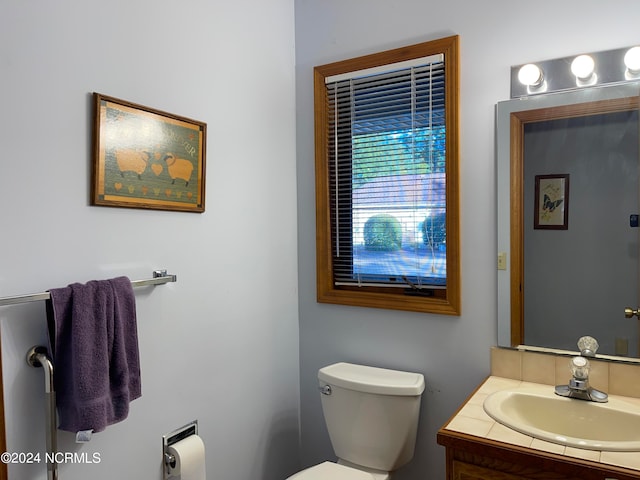 bathroom with toilet and vanity with extensive cabinet space