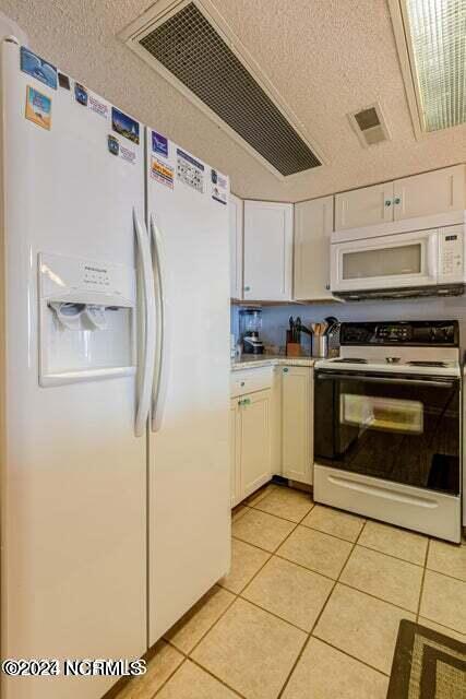 kitchen featuring white appliances, white cabinetry, and light tile flooring