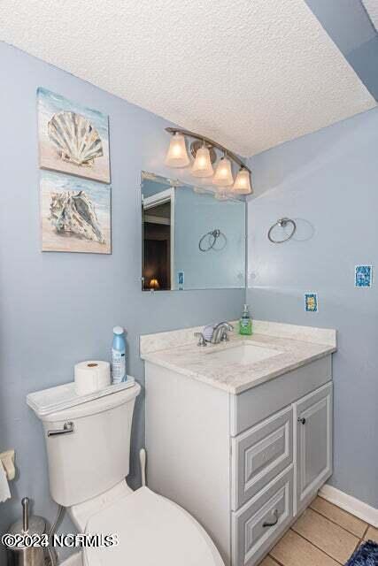 bathroom with tile floors, a textured ceiling, toilet, and vanity