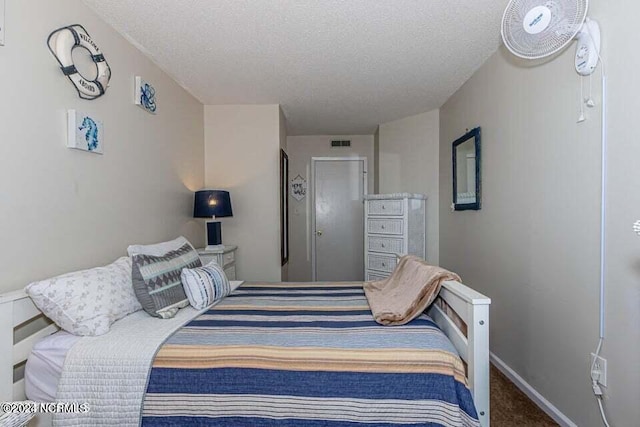 bedroom with a textured ceiling and dark colored carpet