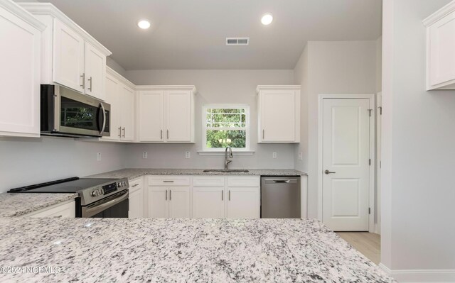 1204 Opaca Dr SE, Bolivia, NC 28422 - kitchen with stainless steel appliances, a sink, white cabinetry, light stone countertops, and recessed lighting