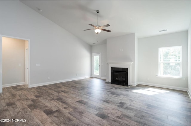 unfurnished living room with visible vents, a fireplace with flush hearth, a ceiling fan, wood finished floors, and high vaulted ceiling