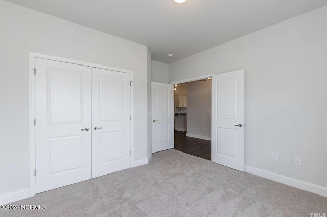 unfurnished bedroom with carpet, a closet, and baseboards