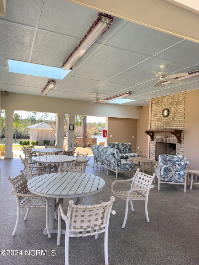 view of patio / terrace featuring an outdoor brick fireplace, outdoor dining space, and ceiling fan