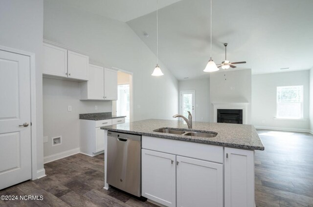 kitchen with light stone counters, white cabinets, a sink, and stainless steel dishwasher