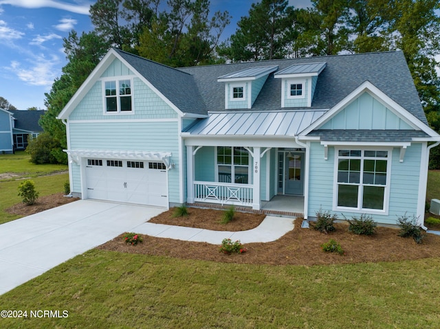 view of front facade with covered porch, a front yard, and a garage