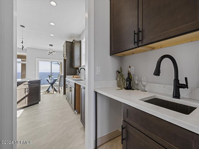 kitchen featuring a water view, dark brown cabinetry, light countertops, and a sink