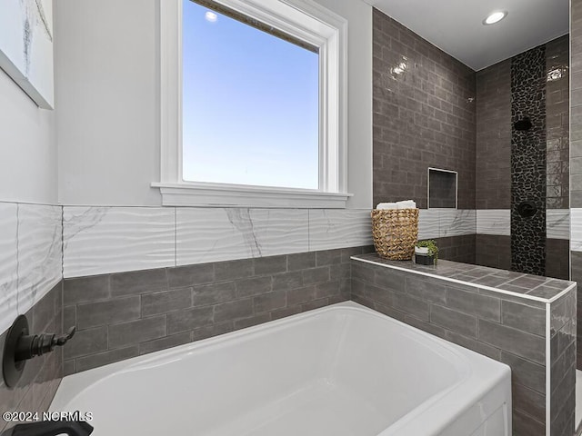 bathroom featuring a washtub and tile walls