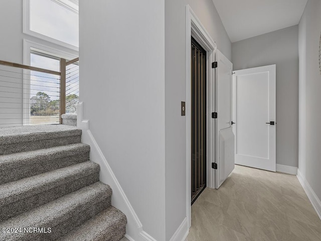 corridor featuring baseboards and stairs