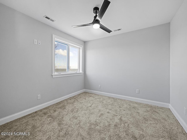 carpeted spare room featuring ceiling fan, visible vents, and baseboards