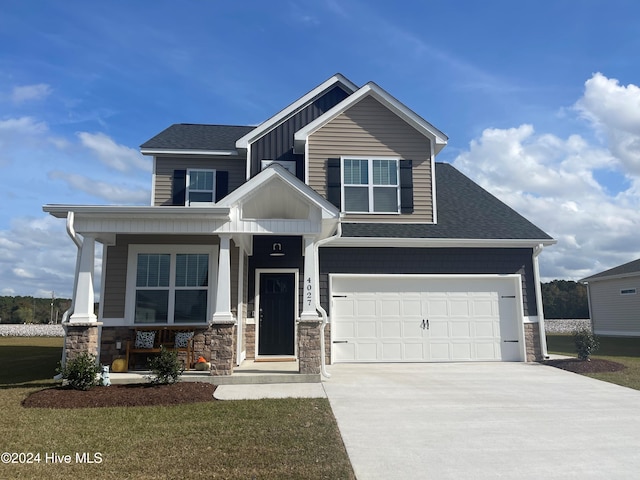 craftsman inspired home with a front lawn, covered porch, and a garage