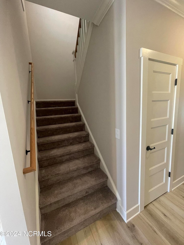 stairway featuring ornamental molding and hardwood / wood-style floors