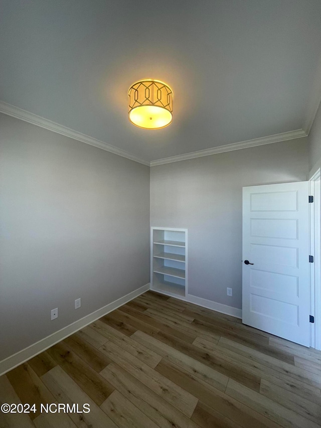 empty room featuring ornamental molding and hardwood / wood-style floors