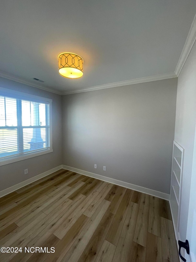 empty room featuring crown molding and light wood-type flooring