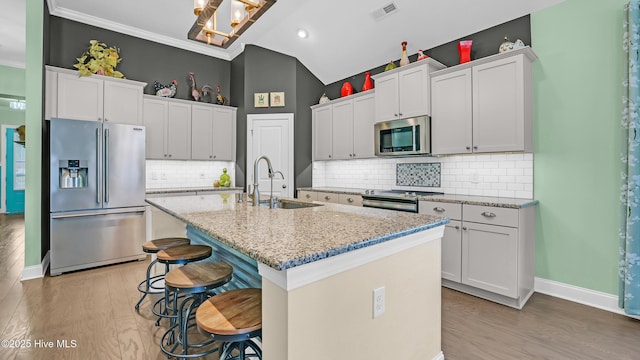 kitchen featuring visible vents, appliances with stainless steel finishes, a sink, a breakfast bar, and light wood-style flooring