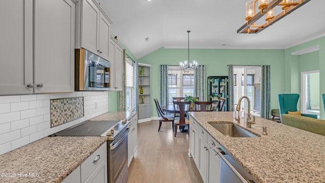kitchen featuring an inviting chandelier, decorative backsplash, light wood-type flooring, a sink, and appliances with stainless steel finishes
