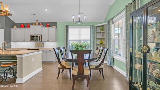 dining room featuring a chandelier, vaulted ceiling, wood finished floors, and visible vents