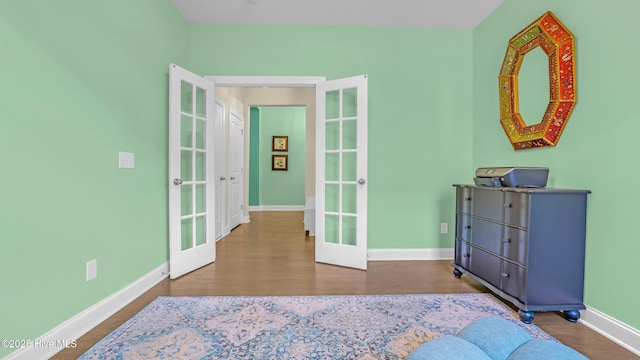 bedroom with baseboards, french doors, and wood finished floors
