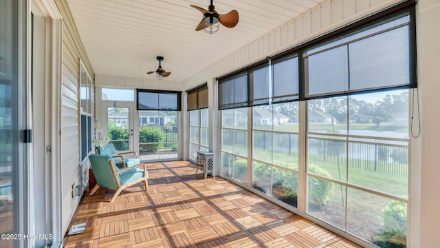 sunroom / solarium with a water view and a ceiling fan