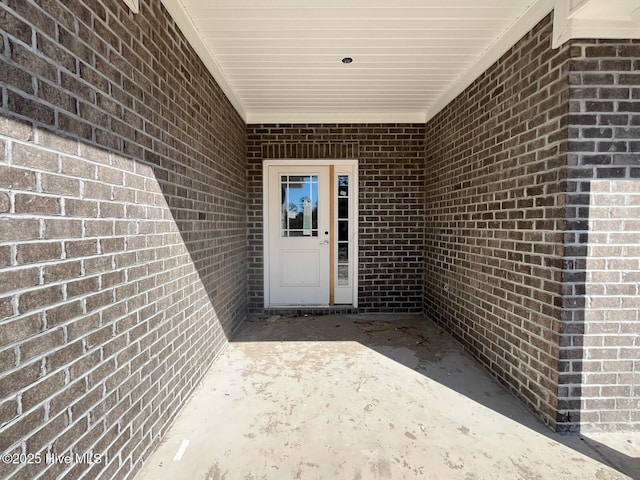 property entrance featuring a patio and brick siding