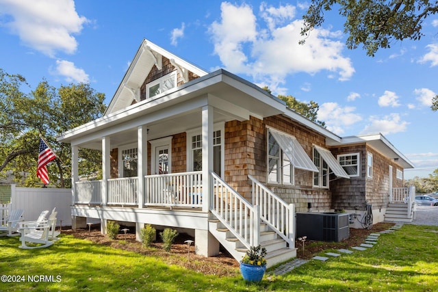 view of side of property featuring a porch, central AC unit, and a lawn