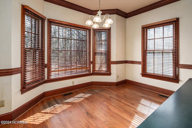 unfurnished dining area featuring plenty of natural light, ornamental molding, and a chandelier