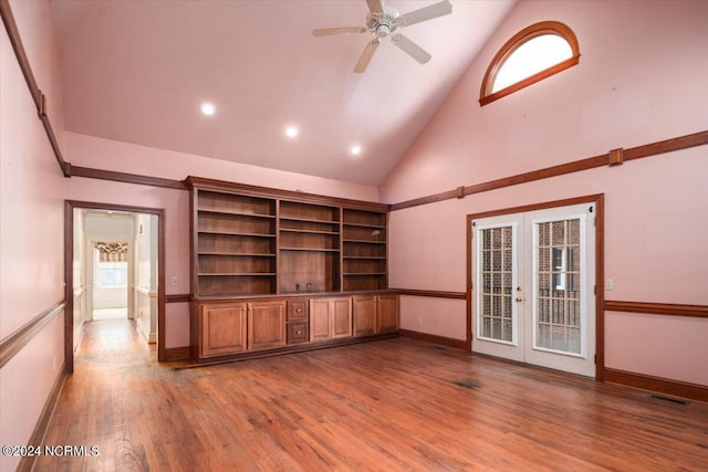 unfurnished living room featuring hardwood / wood-style flooring, ceiling fan, high vaulted ceiling, and french doors