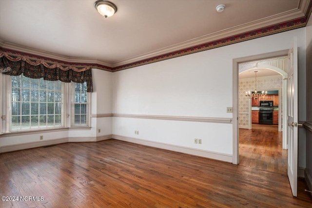 empty room with crown molding, dark hardwood / wood-style floors, and an inviting chandelier