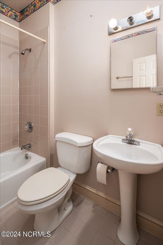 bathroom featuring tile patterned floors, tiled shower / bath combo, and toilet