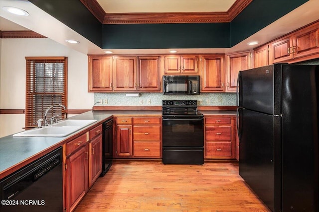 kitchen featuring crown molding, sink, black appliances, and light hardwood / wood-style flooring