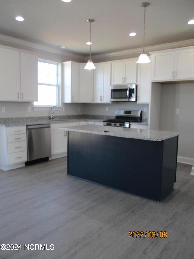 kitchen with white cabinets, hardwood / wood-style floors, hanging light fixtures, and stainless steel appliances