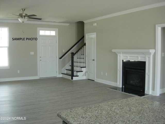 unfurnished living room featuring dark hardwood / wood-style floors, ornamental molding, and ceiling fan