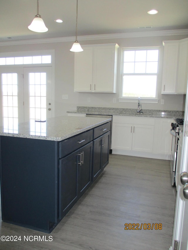 kitchen featuring light hardwood / wood-style floors, decorative light fixtures, white cabinetry, and a wealth of natural light