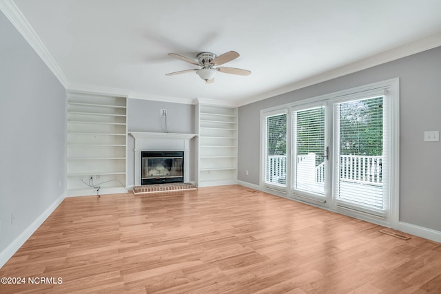 unfurnished living room featuring built in features, ceiling fan, a fireplace, light hardwood / wood-style flooring, and ornamental molding