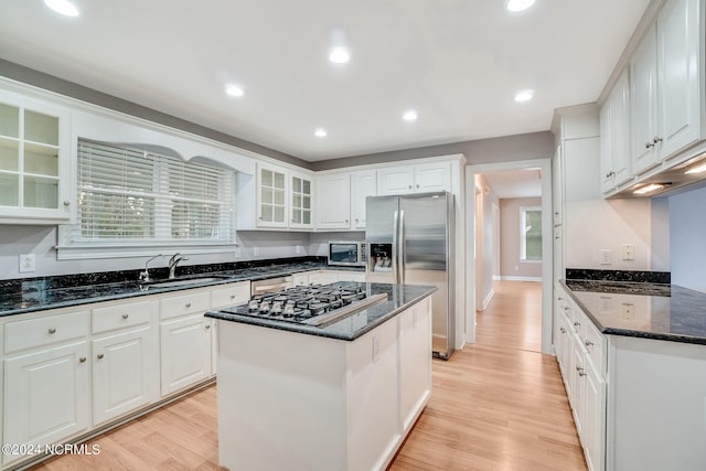 kitchen with white cabinetry, light hardwood / wood-style flooring, a center island, and dark stone countertops