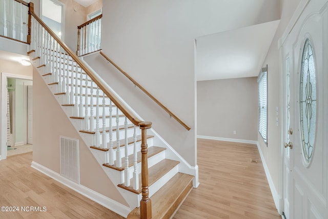 foyer with a towering ceiling, light wood-type flooring, and a healthy amount of sunlight