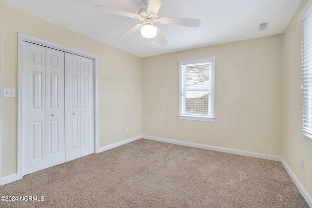 unfurnished bedroom with light colored carpet, a closet, and ceiling fan