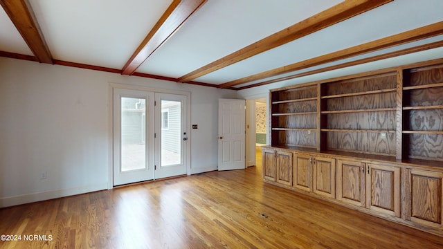 spare room featuring light wood-type flooring, french doors, and beamed ceiling