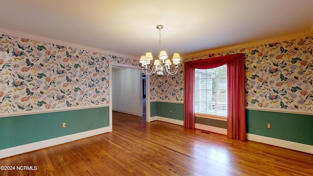 empty room with dark hardwood / wood-style floors, an inviting chandelier, and ornamental molding